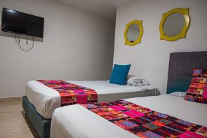 a room with two beds and a flat screen tv at Hotel Veneton Dosquebradas in Dosquebradas