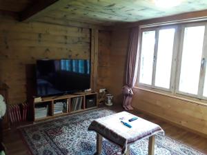 a living room with a flat screen tv and a table at DesAlpes in Saxeten