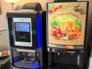 a computer next to a drink dispenser with a picture of fruit at Brit Hotel Essentiel Pau Lescar in Lescar