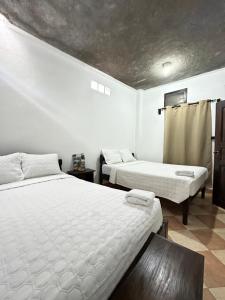 two beds in a room with white walls at Guest House Don Moisés in Copán Ruinas