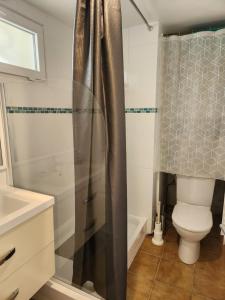 a bathroom with a shower curtain and a toilet at Côté Plage in Saint-Marcouf