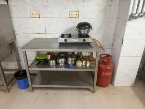 a small kitchen with a stove with pots and pans at Gulnaar Inn Near US Counsulate Sankar nethralaya Apollo Hospital in Chennai +15 photos