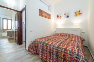 a white bedroom with a bed and a mirror at Appartamento il Decimomiglio in Decimomannu