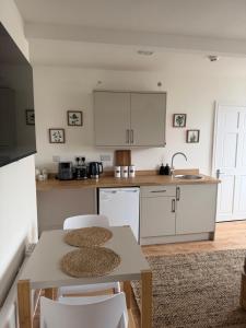 a kitchen with white cabinets and a table and chairs at Glan Neigr Room 11 in Rhosneigr