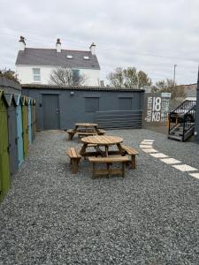 a group of picnic tables on a gravel patio at Glan Neigr Room 11 in Rhosneigr