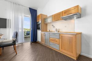 a kitchen with wooden cabinets and a table and a desk at Lotus Oliva Apart in Premantura