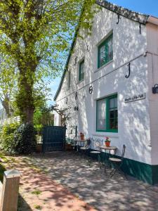 a white building with tables and chairs in front of it at Ferienwohnung Krabbe in Manslagt