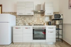 a kitchen with white cabinets and a white refrigerator at Appartamento il Decimomiglio in Decimomannu