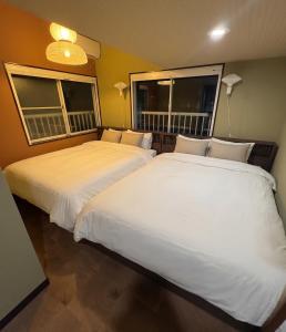 two white beds in a room with two windows at Shinjuku Topshot Hotel in Tokyo