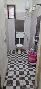 a bathroom with a toilet and a pink bucket at Godavari Lodge in Solapur +37 photos