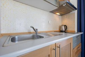 a kitchen with a stainless steel sink and tiles at Lotus Oliva Apart in Premantura +36 photos