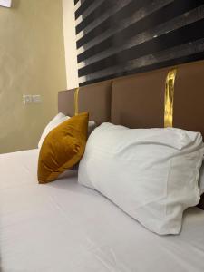 a bed with white sheets and yellow pillows at Max Heron, Gorgeous 2 Bedroom in Ikeja +30 photos