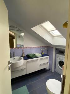a bathroom with a sink and a washing machine at La casetta sui tetti in Alba