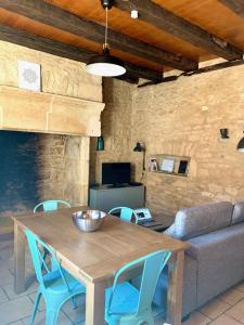 a wooden table with blue chairs and a couch at La pomponnaise in Saint-Pompont