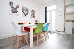 a kitchen with a white table with colorful chairs at Borough Street in Port Talbot