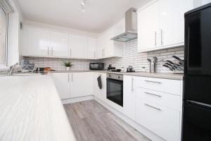 a white kitchen with white cabinets and a black refrigerator at Borough Street in Port Talbot