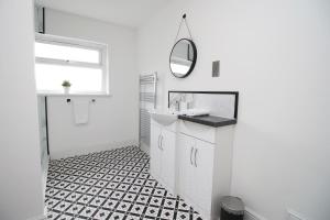 a white bathroom with a sink and a mirror at Borough Street in Port Talbot