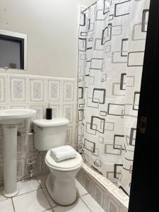 a bathroom with a toilet and a shower curtain at Guest House Don Moisés in Copán Ruinas