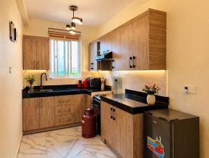 a kitchen with wooden cabinets and a black refrigerator at Nuellas Haven in Kira