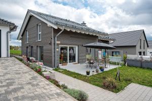 a house with a patio with a table and an umbrella at Ferienhaus Seewald in Seewald