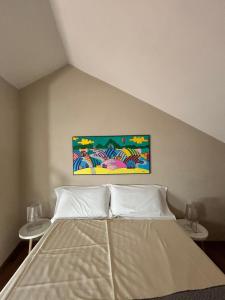 a bedroom with a bed with a painting on the wall at La casetta sui tetti in Alba