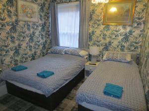 two twin beds in a room with wallpaper at The Salendine in Blackpool