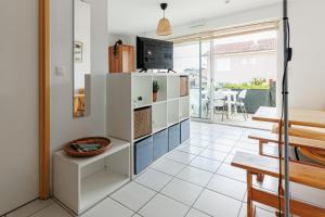 a kitchen with white cabinets and a dining room with a table at Aux Gourbets - Conciergerieland in Vieux-Boucau-les-Bains