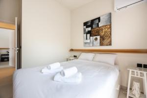 a bedroom with a white bed with white towels on it at Aelion Airport Residence By SEM in Artemida