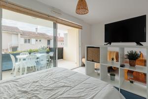 a bedroom with a television and a table with chairs at Aux Gourbets - Conciergerieland in Vieux-Boucau-les-Bains