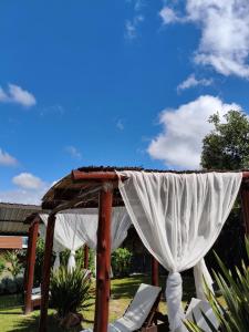 a gazebo with white curtains and chairs at Cabañas Thijada in Mina Clavero