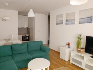 a living room with a green couch and a kitchen at Stan in Zrenjanin