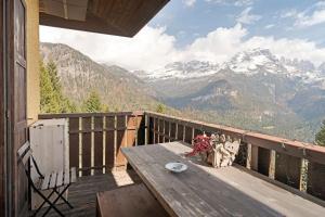 a wooden table on a balcony with a view of mountains at Relax At The Mountain in Madonna di Campiglio