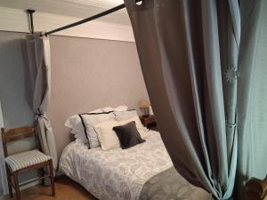a bedroom with a bed with a canopy and a chair at Gîte La Belle du Clocher in Saint-Pardoux-dʼArnet