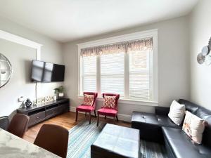 a living room with a black couch and two red chairs at Carytown nest King Bed fully fenced in Richmond