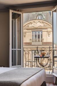 a bedroom with a balcony with a table and a balcony at Hotel Montalembert in Paris