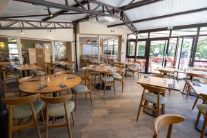 a restaurant with wooden tables and chairs and windows at Club Vacances Bleues Domaine de Château Laval in Gréoux-les-Bains