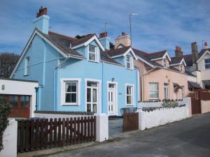 a blue house with a fence in front of it at Ty Haf in Rhosneigr