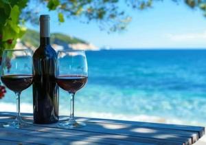 two glasses of wine sitting on a table next to the ocean at Apartmani Antula in Prigradica