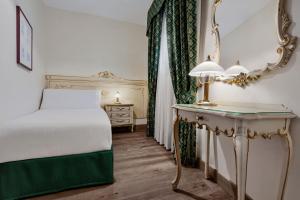 a bedroom with a bed and a table with a mirror at Hotel Commercio & Pellegrino in Venice