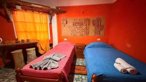 two beds in a room with red walls at Maité Hospedaje in Santa María