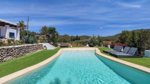 a swimming pool with two blue chairs and a house at Villa Radi by Eivillas in Santa Gertrudis de Fruitera