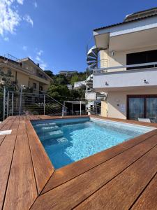 ein Swimmingpool mit Holzterrasse neben einem Haus in der Unterkunft Formia Bellevue in Formia