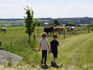 two children standing in a field looking at cows at Ferienhof Forstmoar in Gars am Inn