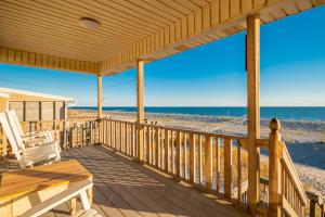 a wooden porch with a bench and the beach at Lady Dune in Oak Island