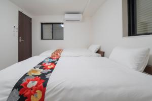 a bedroom with a white bed with a floral blanket on it at the UNIT5 HOUSE Roppongi in Tokyo