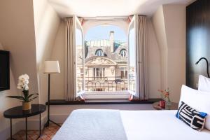a bedroom with a bed and a window with a building at Hotel Montalembert in Paris