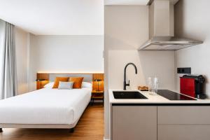a bedroom with a bed and a kitchen with a sink at Apartamentos 2H LIVING in León +80 photos