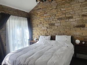 a bedroom with a large bed with a brick wall at Edgerton cottage, large 1-bed detached coach house in town, Spacious rustic charm in Lindley
