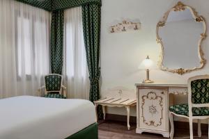 a bedroom with a bed and a desk and a mirror at Hotel Commercio & Pellegrino in Venice