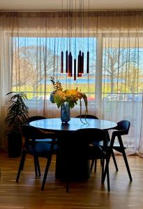 a dining room table with chairs and a vase with flowers at Seafront Lux Apt, Central, Beach, Direct Airport Metro in Copenhagen
